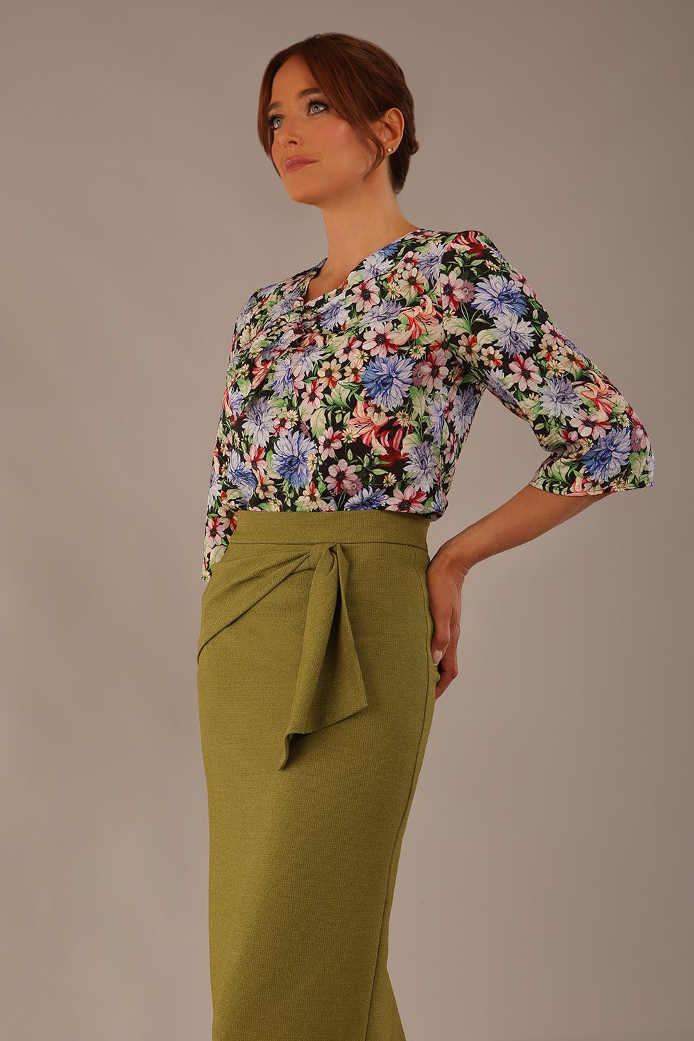 Model wearing a Suki asymmetric draped top in the Aurora Botanical print, styled with a olive green pencil skirt.