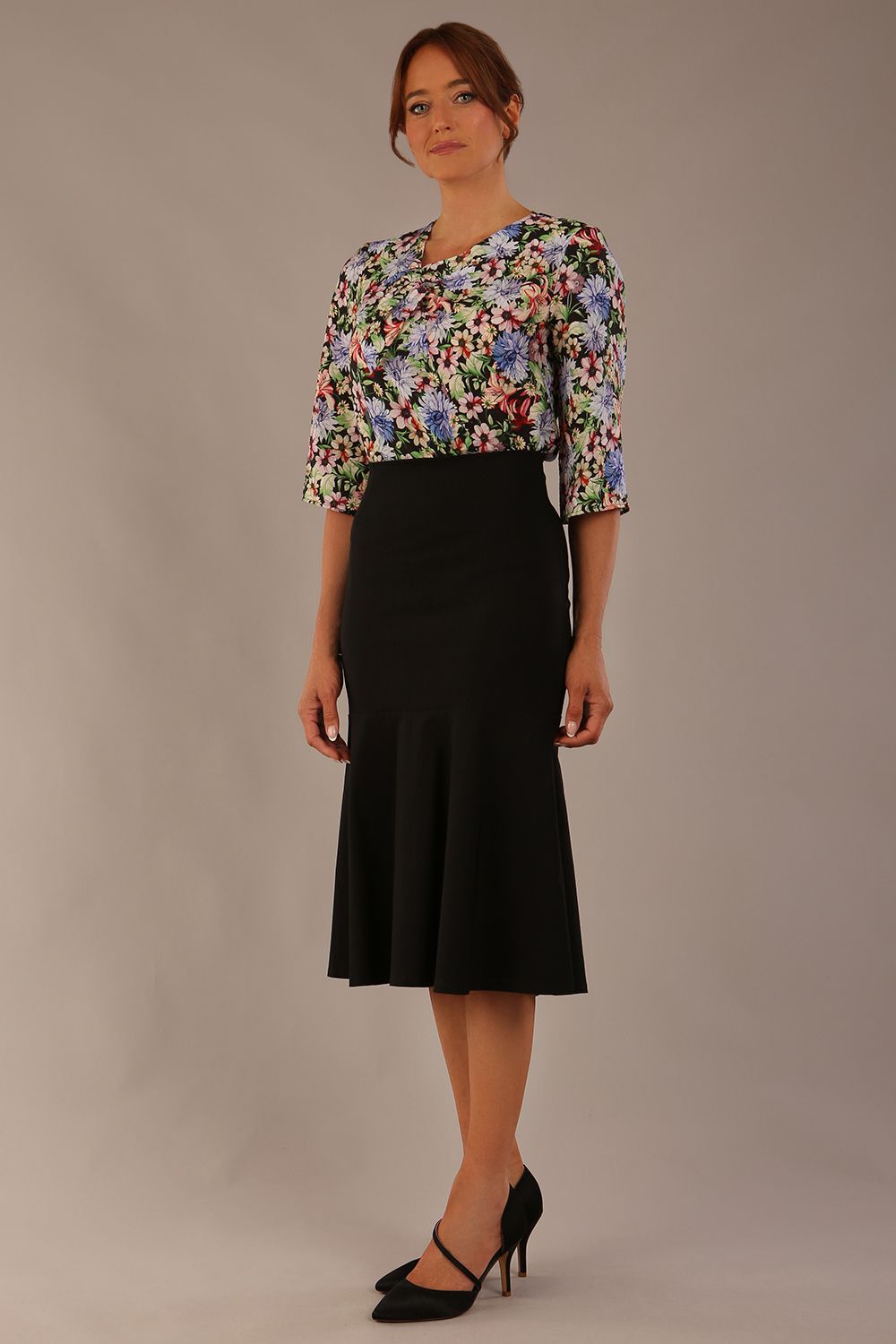 Model wearing a Suki asymmetric draped top in the Aurora Botanical print, styled with a black fishtail skirt.