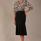 Model wearing a Suki asymmetric draped top in the Aurora Botanical print, styled with a black fishtail skirt.