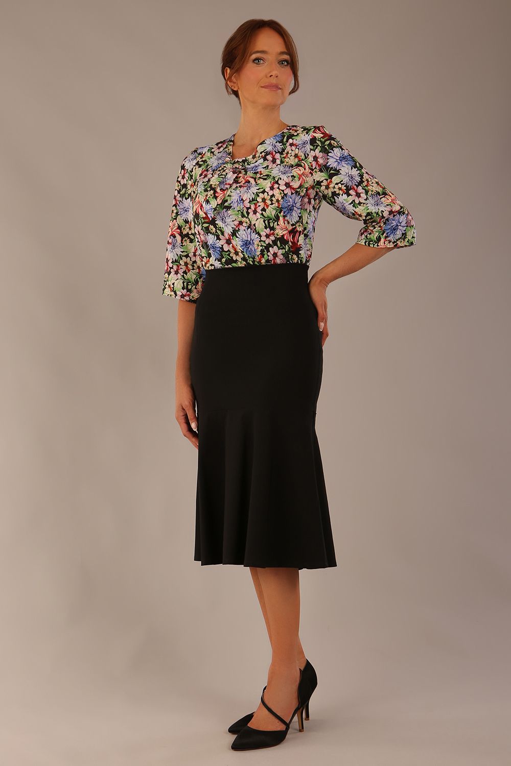 Model wearing a Suki asymmetric draped top in the Aurora Botanical print, styled with a black fishtail skirt.