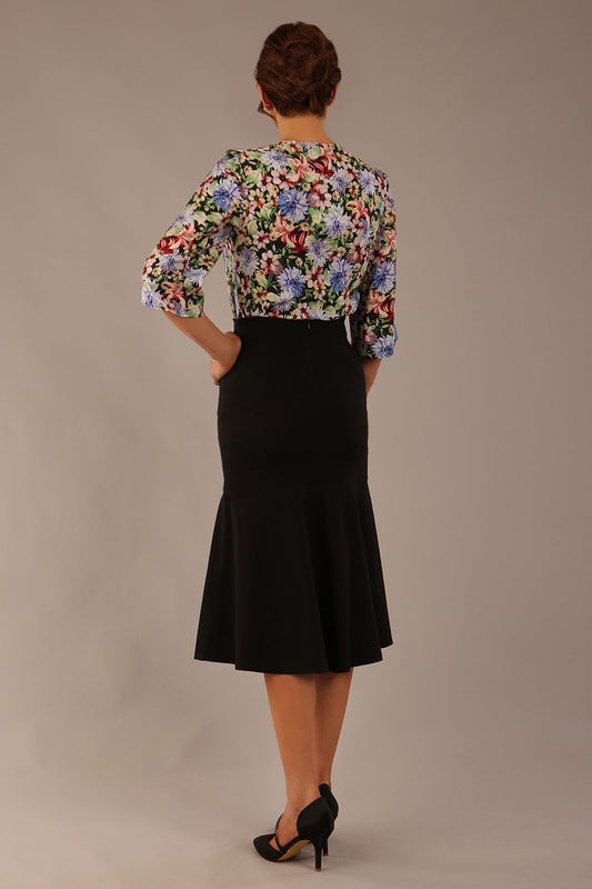 Model wearing a Suki asymmetric draped top in the Aurora Botanical print, styled with a black fishtail skirt.