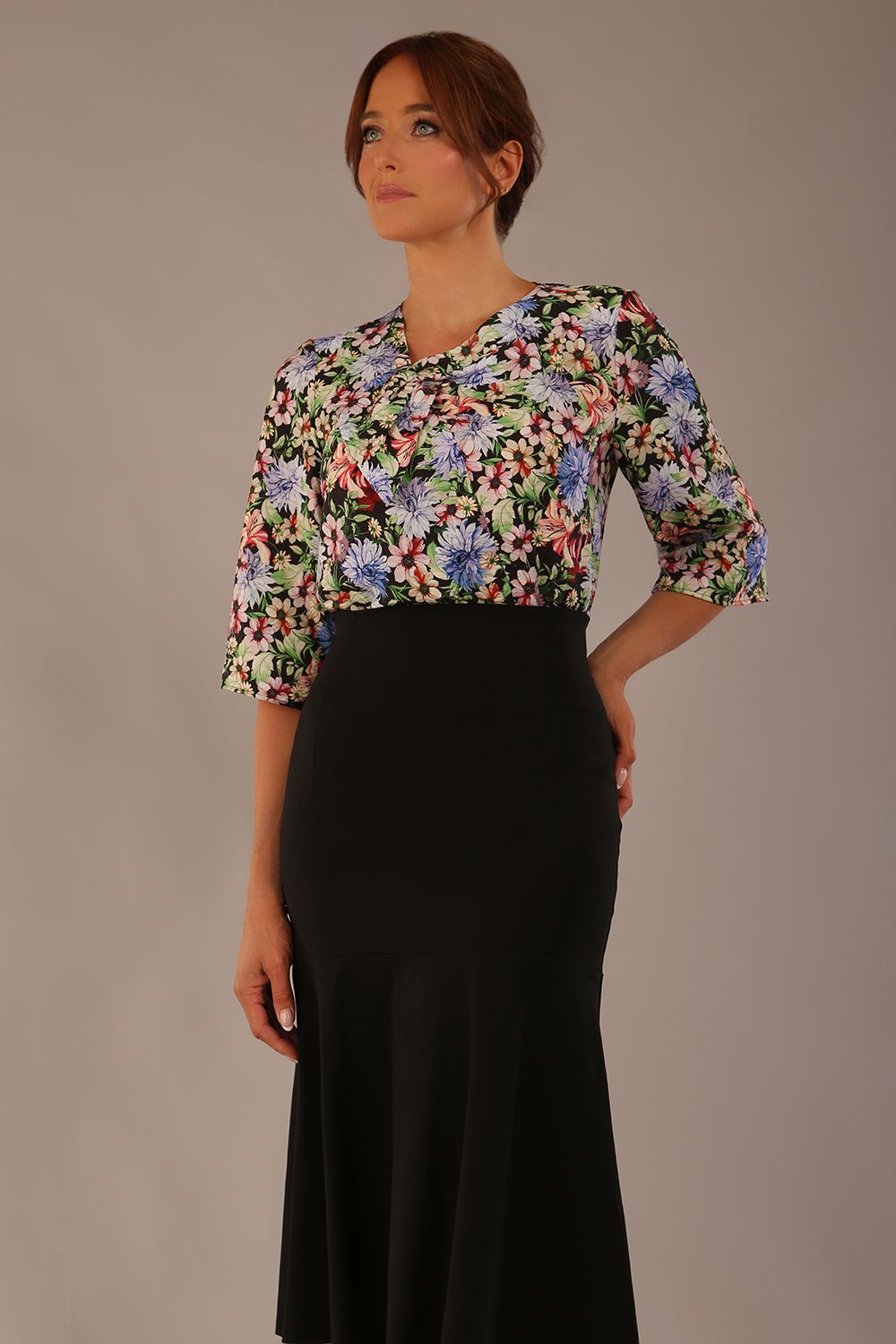 Model wearing a Suki asymmetric draped top in the Aurora Botanical print, styled with a black fishtail skirt.