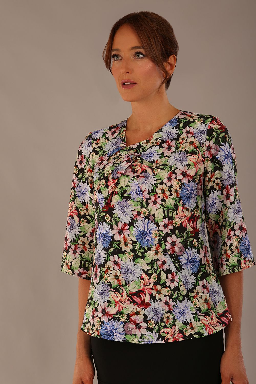 Model wearing a Suki asymmetric draped top in the Aurora Botanical print, styled with a black fishtail skirt.