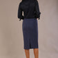 Model wearing a navy satin pebble top with a tie neckline and 3/4 sleeves, styled with a navy pencil skirt.