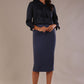 Model wearing a navy satin pebble top with a tie neckline and 3/4 sleeves, styled with a navy pencil skirt.
