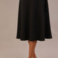 Model wearing the Harlow A-line midi skirt in black, with the side-tie fastened in a bow.
