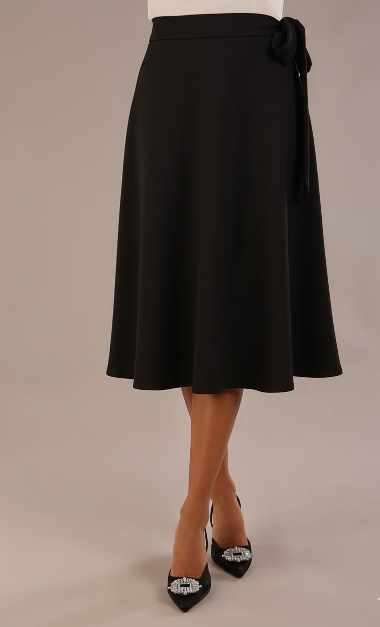 Model wearing the Harlow A-line midi skirt in black, with the side-tie fastened in a bow.