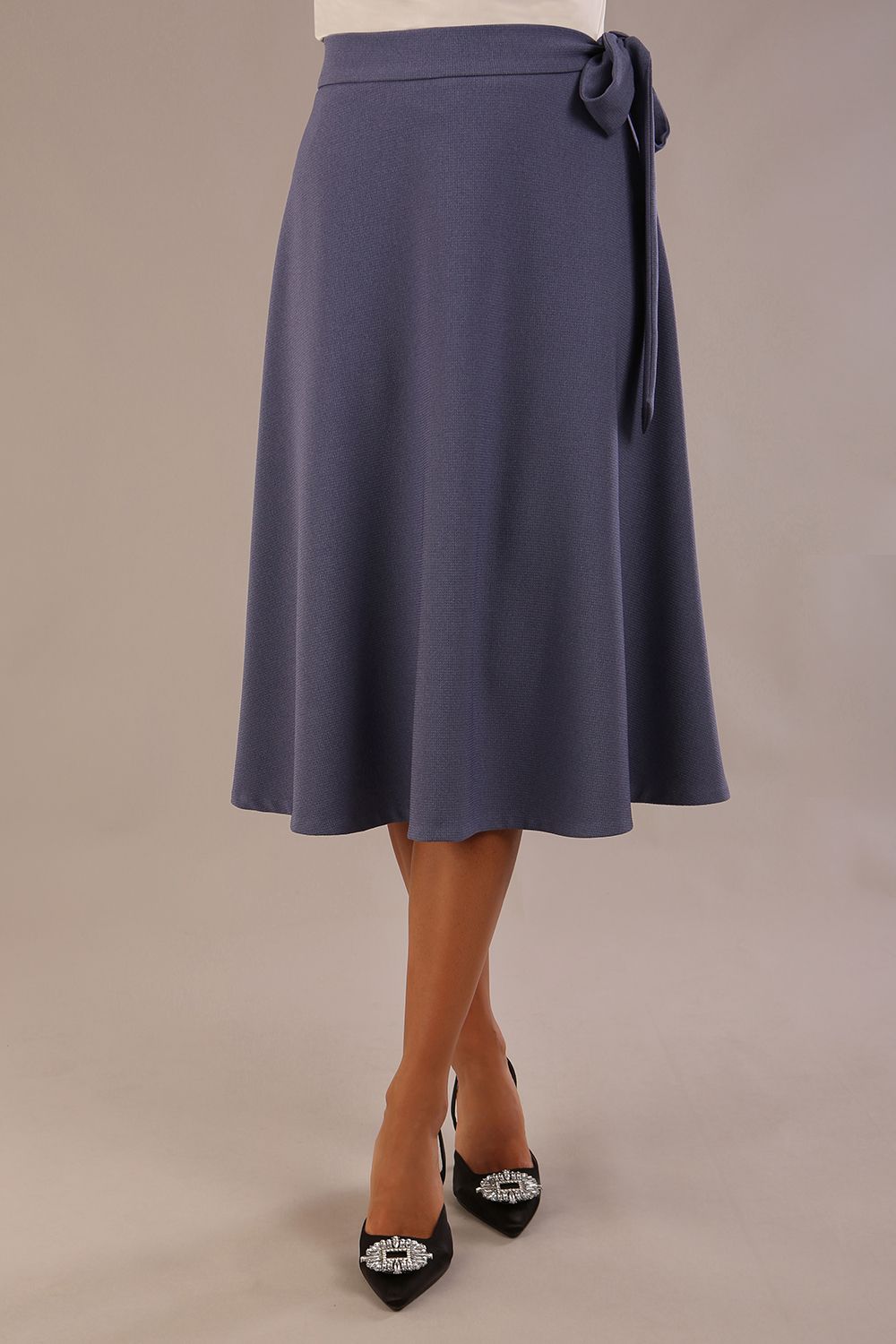 Model wearing the Harlow A-line midi skirt in blue mineral, with the side-tie fastened in a bow.