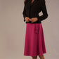 Model wearing the Harlow A-line midi skirt in festive fuchsia, with the side-tie fastened in a bow with a black jacket