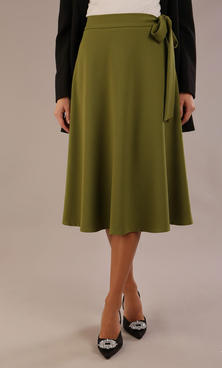 Model wearing the Harlow A-line midi skirt in oasis green, with the side-tie fastened in a bow.