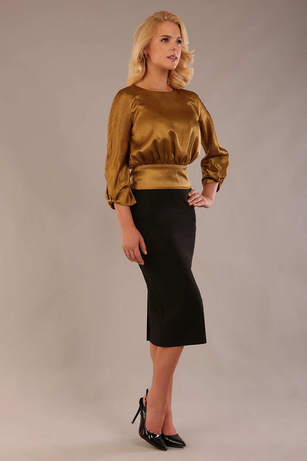 Model wearing a Hollywood lustre gold top with a blouson silhouette and a black pencil skirt front side