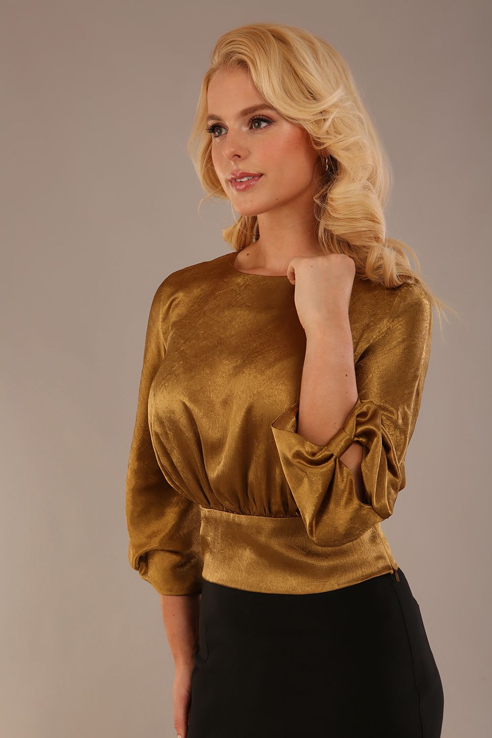 Model wearing a Hollywood lustre gold top with a blouson silhouette and a black pencil skirt close up