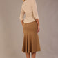 Model wearing a Trina wrap top in almond cream, with a wide V-neck and 3/4 sleeves, styled with a camel fishtail skirt.