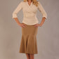 Model wearing a Trina wrap top in almond cream, with a wide V-neck and 3/4 sleeves, styled with a camel fishtail skirt.