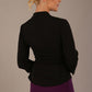 Model wearing a Trina wrap top in black, with a wide V-neck and 3/4 sleeves, styled with a purple pencil skirt back view