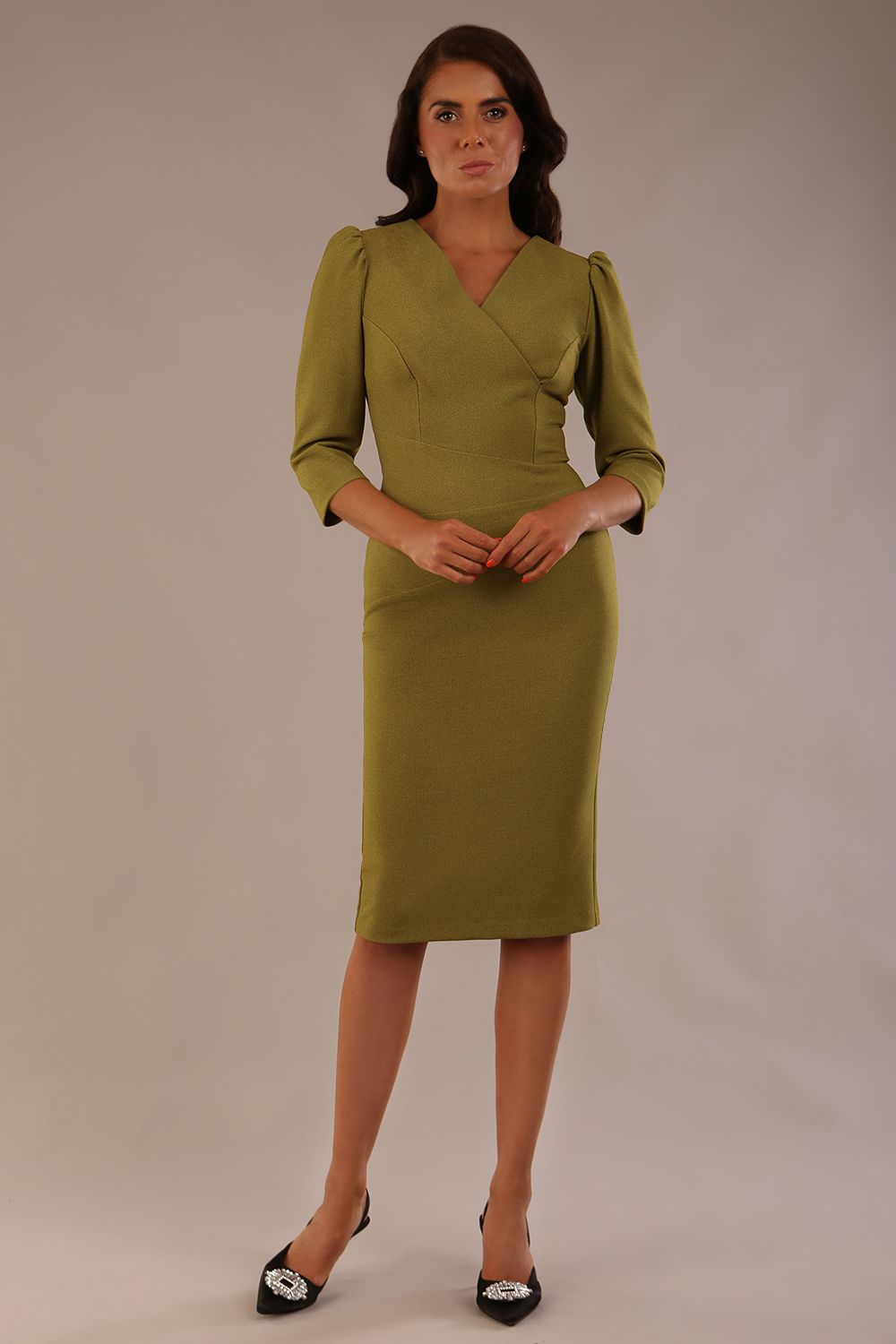 Model wearing an Ethan V-neck dress in oasis green, highlighting the flattering seams and puff shoulders.