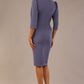 Model wearing a blue mineral Ethan dress, styled with white heels back view