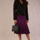 Model wearing a Teddy Luxe Boucle Jacket in black and purple skirt holding a black handbag against a plain background