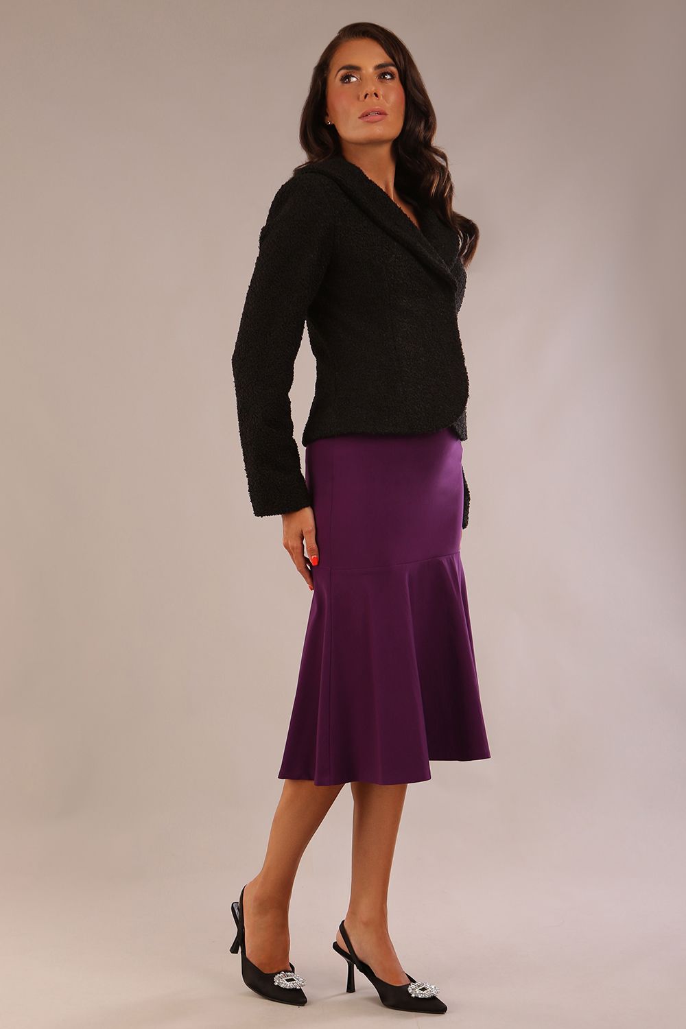 Full-length view of the Teddy jacket in black paired with a matching fishtail skirt in purple.