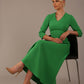  sitting Model wearing the Nova V-neck A-line midaxi dress in vibrant jelly bean green