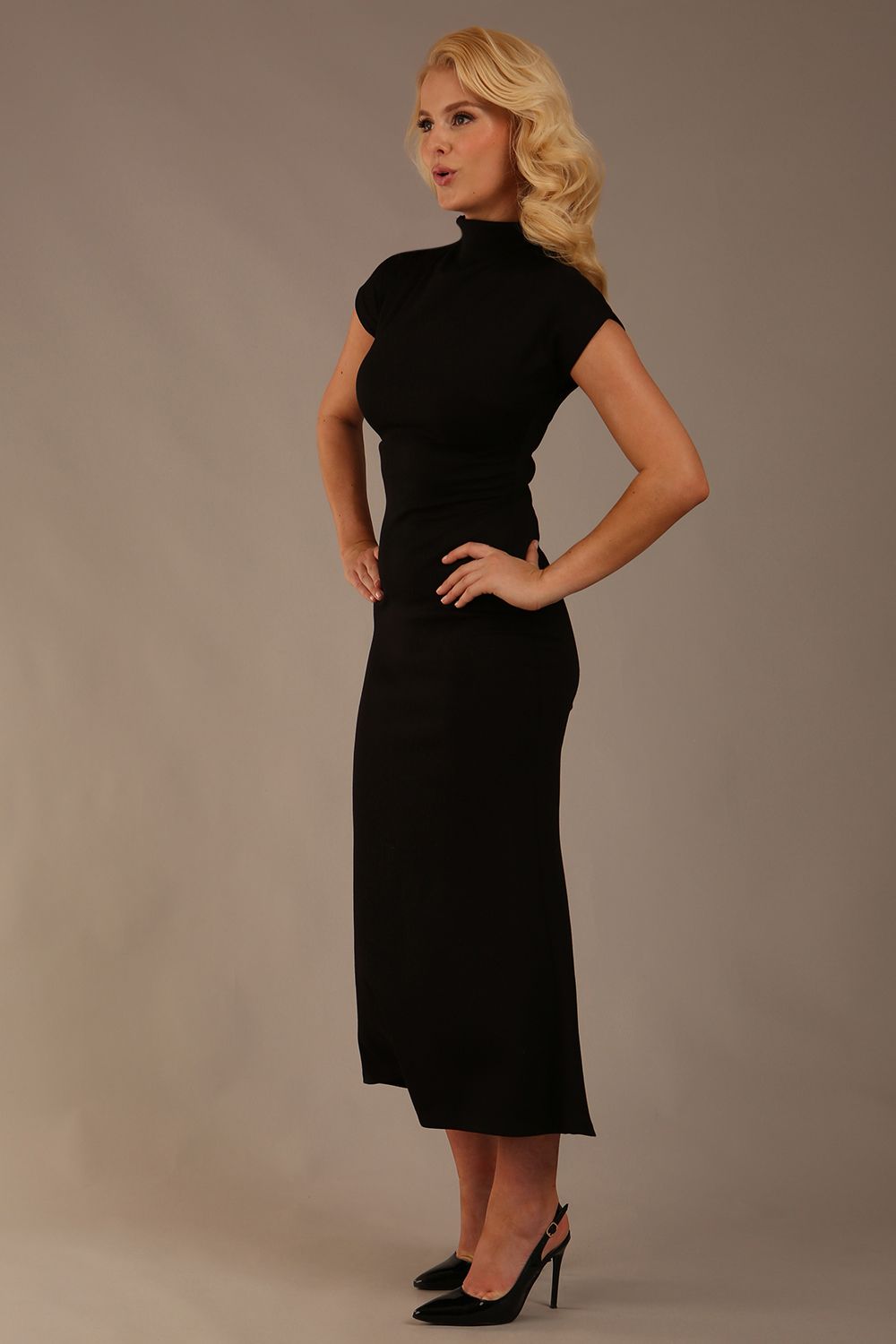 Model wearing the Kaden high neck midaxi dress in jet black, showing the sleek silhouette and cap sleeves. against a plain background