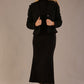 Woman wearing a black outfit with a textured jacket and the Kaden high neck midaxi dress in jet black, showing the sleek silhouette and cap sleeves against a plain background 