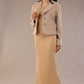 Woman wearing a beige outfit with a textured jacket and the Kaden high neck midaxi dress in cafe au lait cream, showing the sleek silhouette and cap sleeves against a plain background 