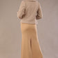 Woman wearing a beige outfit with a textured jacket and the Kaden high neck midaxi dress in cafe au lait cream, showing the sleek silhouette and cap sleeves against a plain background  back view