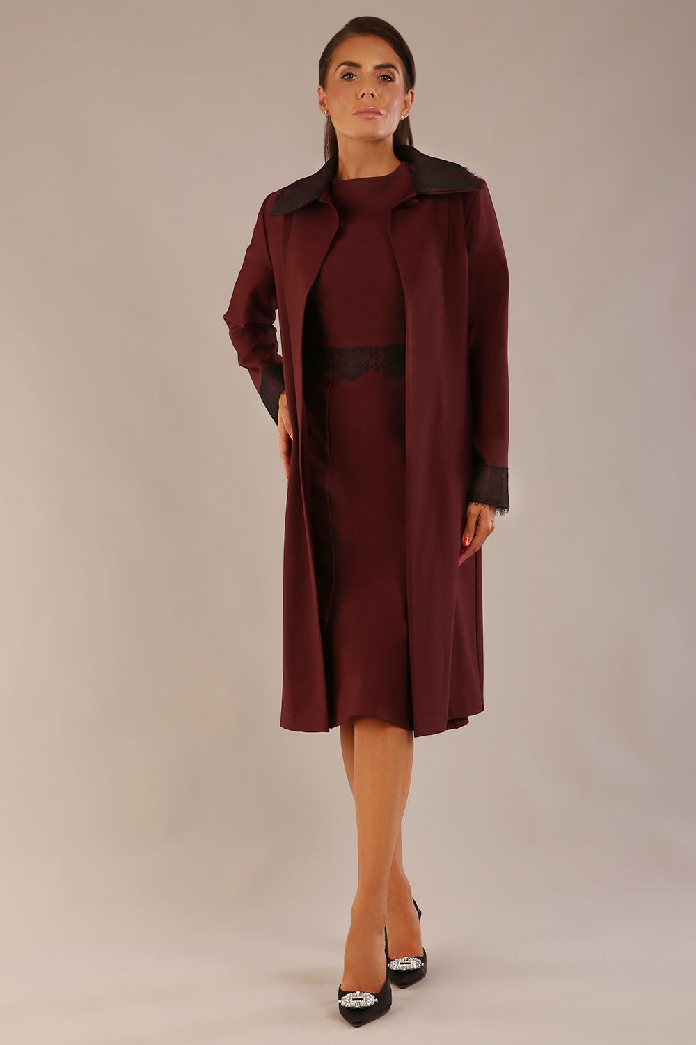 Model wearing the Lovell dress in port royale, showcasing the fluted sleeves and black lace waistband against a beige background styled with the Haven Lace Trim Coat in the same colour