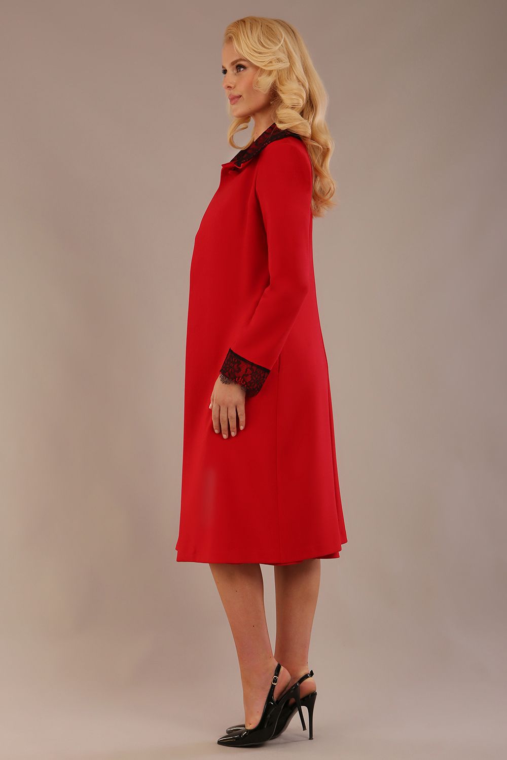 Side view of the Haven coat in salsa red, showing the lace cuff detail and the fluid drape of the couture fabric.
