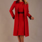 Model wearing the Lovell dress in salsa red, showcasing the fluted sleeves and black lace waistband against a beige background styled with the Haven Lace Trim Coat in the same colour