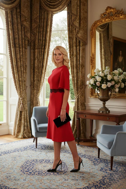 Model wearing the Lovell dress in salsa red, showcasing the fluted sleeves and black lace waistband against a beige background (Salsa Red)