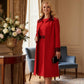Model wearing the Lovell dress in salsa red, showcasing the fluted sleeves and black lace waistband against a beige background (Salsa Red)