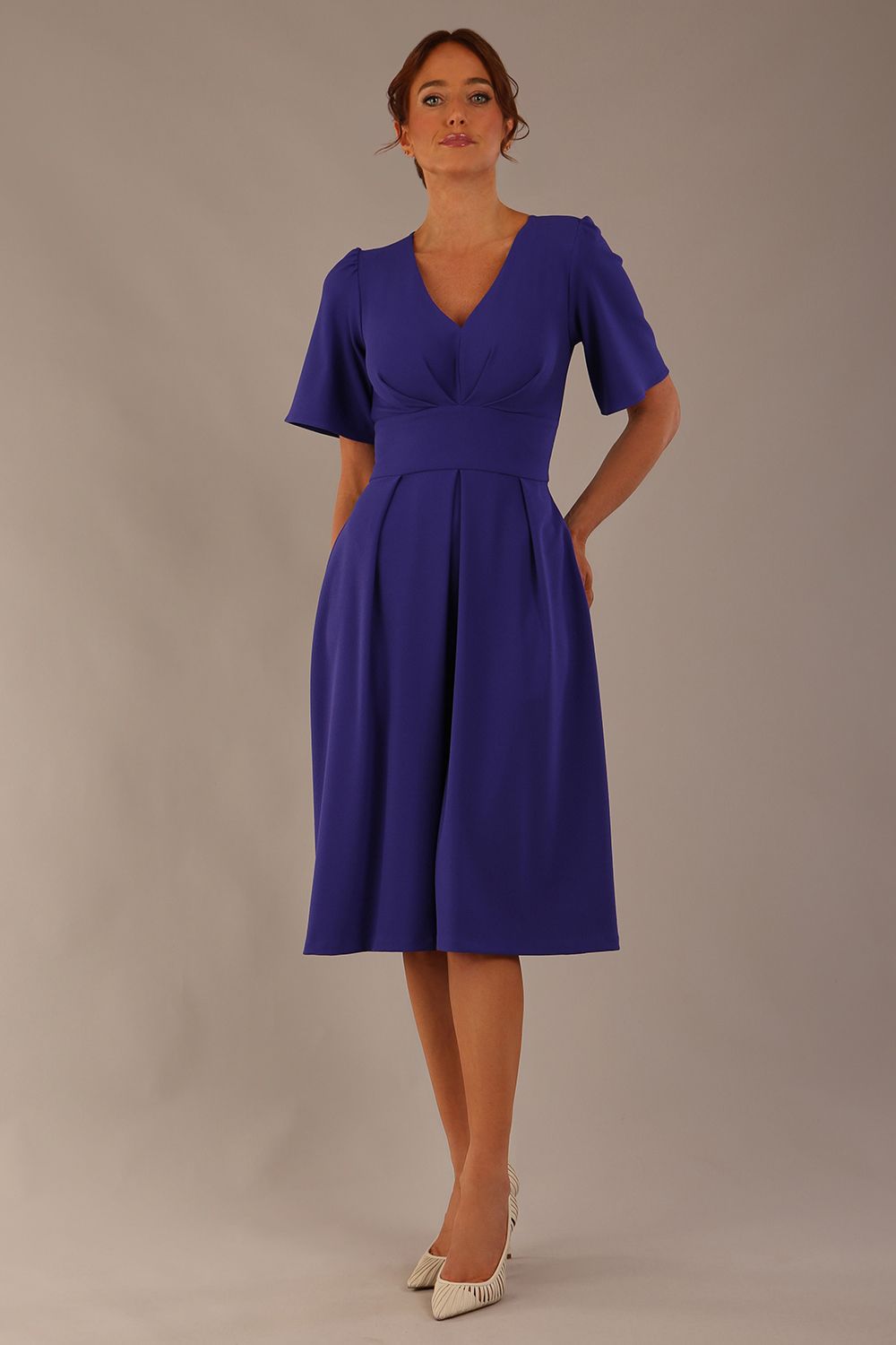 Model wearing the Dale pleated A-line dress against a plain background (Spectrum Indigo)