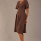Model wearing the Dale pleated A-line dress against a plain background (Peppercorn Brown)