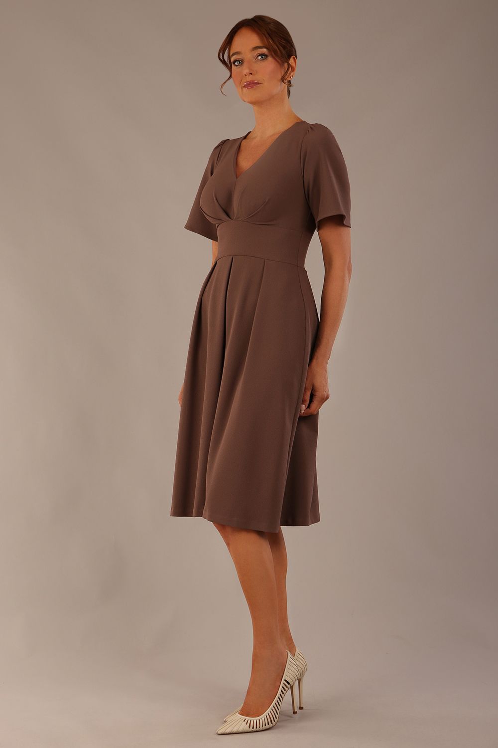 Model wearing the Dale pleated A-line dress against a plain background (Peppercorn Brown)