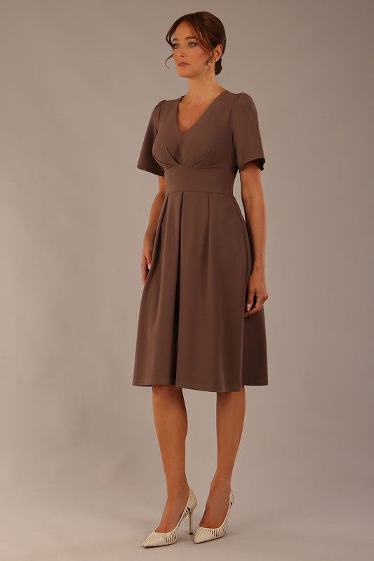 Model wearing the Dale pleated A-line dress against a plain background (Peppercorn Brown)