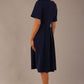 Back view of the Model wearing the Dale pleated A-line dress against a plain background (Navy Blue)