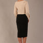 model wearing a Cressida long sleeve top in almond cream, with a boat neckline and asymmetric bow, styled with a black skirt back view