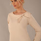 model wearing a Cressida long sleeve top in almond cream, with a boat neckline and asymmetric bow, styled with a black skirt close up view