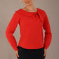 model wearing a Cressida long sleeve top in poppy red, with a boat neckline and asymmetric bow, styled with a pencil skirt front view