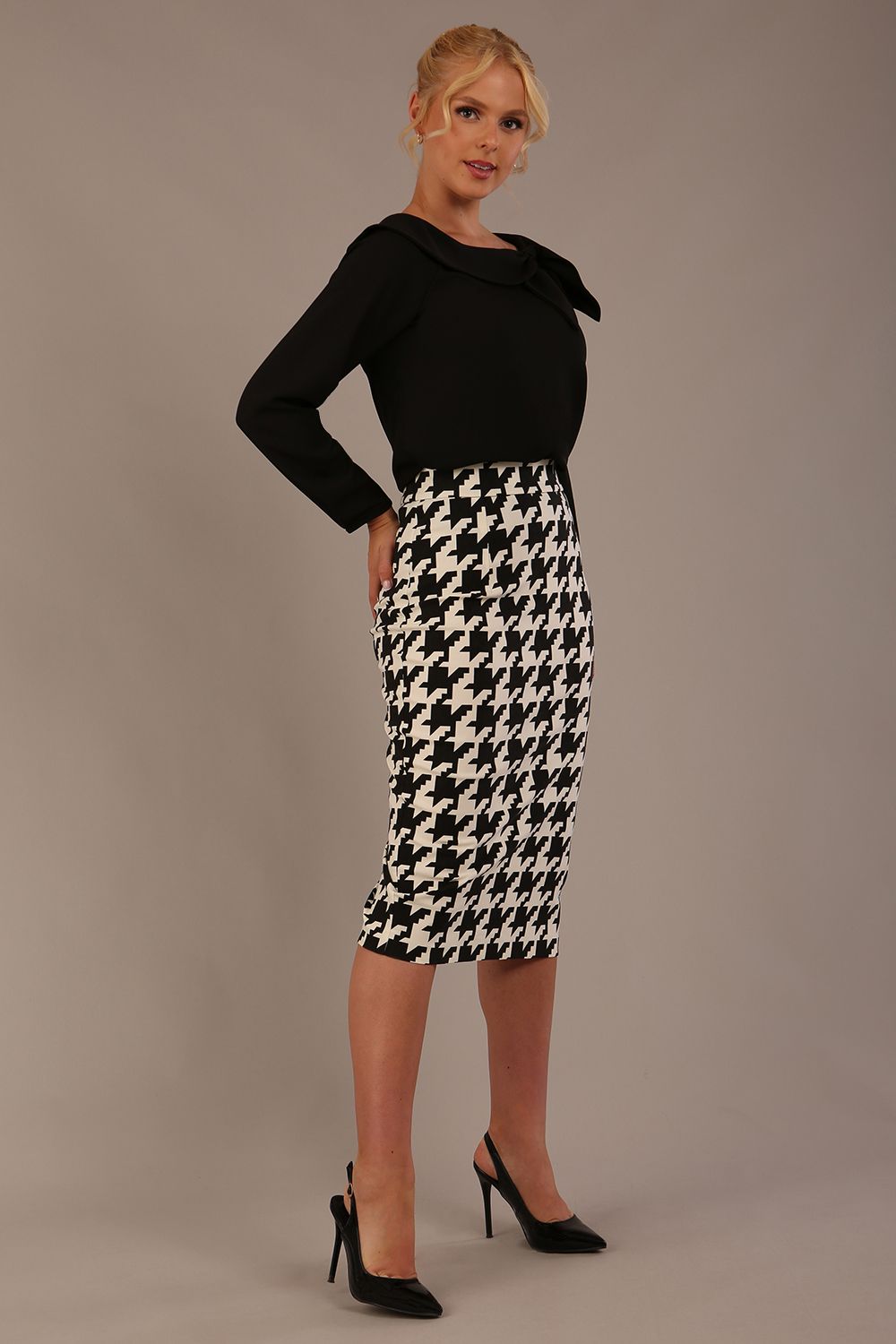 Woman wearing a divacatwalk cressida black top and houndstooth patterned skirt against a plain background