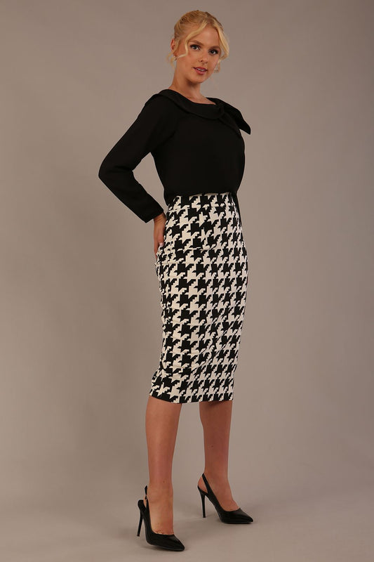 Woman wearing a divacatwalk cressida black top and houndstooth patterned skirt against a plain background