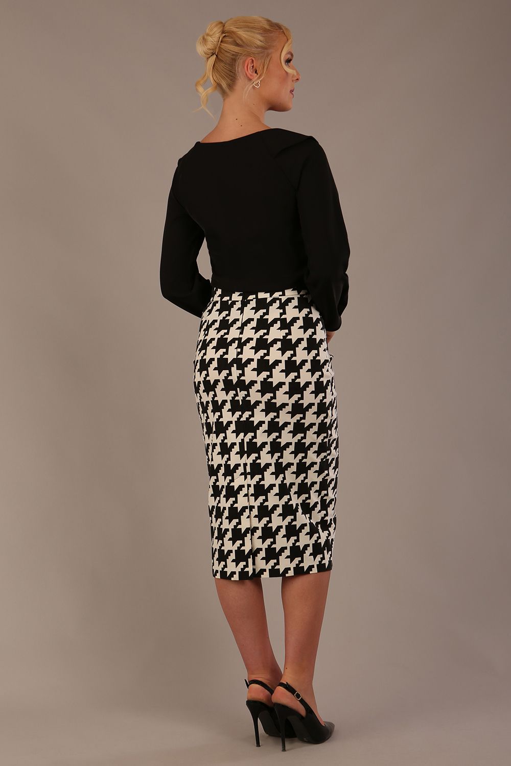 Woman wearing a diva catwalk cressida black top and houndstooth skirt against a neutral background back view