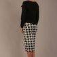 Woman wearing a diva catwalk cressida black top and houndstooth skirt against a neutral background side back view