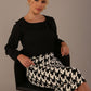 Woman sitting on a chair wearing a diva catwalk cressida black top and houndstooth-patterned skirt against a plain background (Houndstooth print)