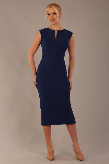 Model wearing the Wesley notched pencil dress in navy blue, showcasing the sculpted silhouette and V-notch neckline