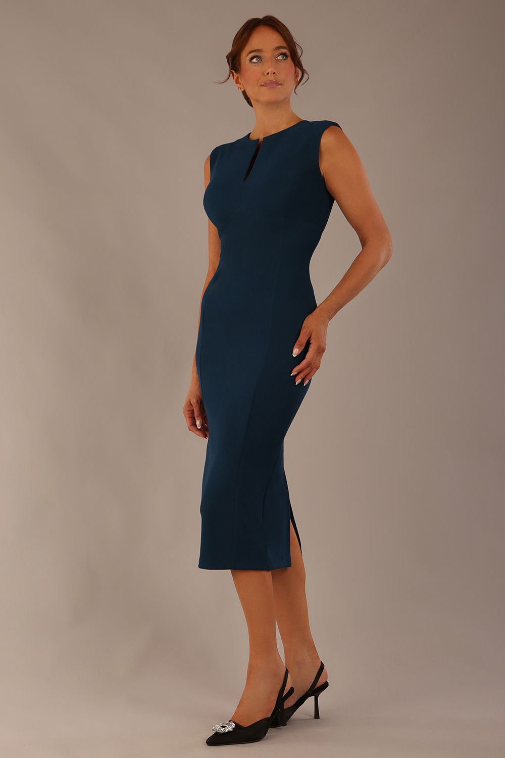 Model wearing the Wesley notched pencil dress in teal, showcasing the sculpted silhouette and V-notch neckline side view