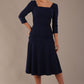 Model wearing the Rowan dress in navy blue, showing the square neckline and ruched bodice.