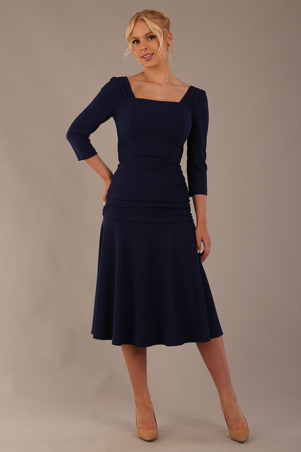 Model wearing the Rowan dress in navy blue, showing the square neckline and ruched bodice.